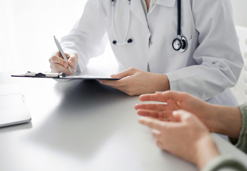 Doctor-completing-patient-paperwork-during-consultation Doctor-completing-patient-paperwork-during-consultation