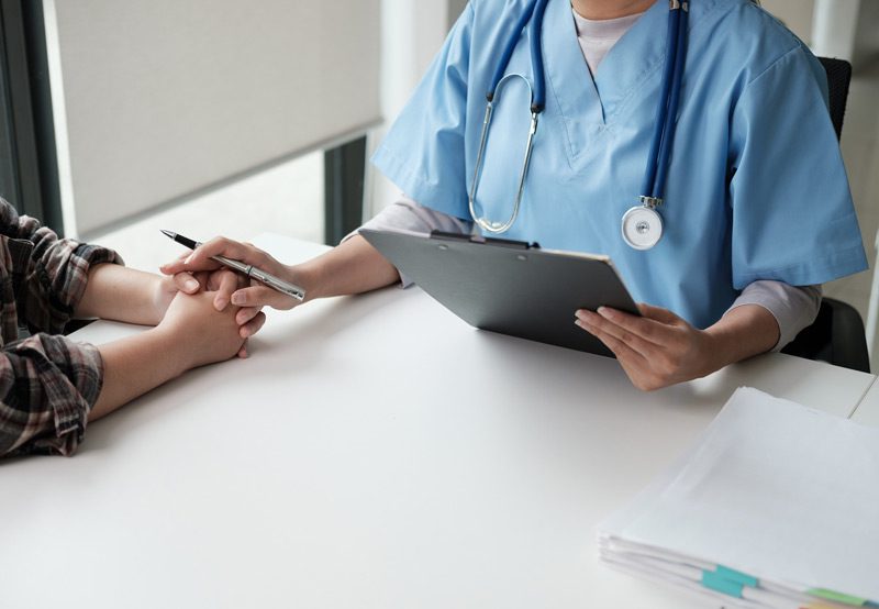 Doctor-consulting-with-patient-at-desk Doctor-consulting-with-patient-at-desk