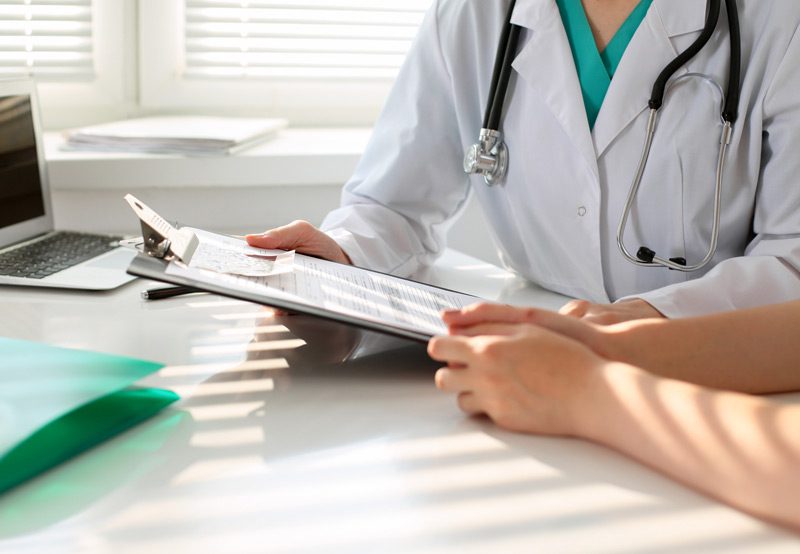 Doctor-reviewing-patient-records-with-clipboard Doctor-reviewing-patient-records-with-clipboard