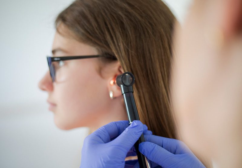 Doctor-using-otoscope-to-check-woman's-ear