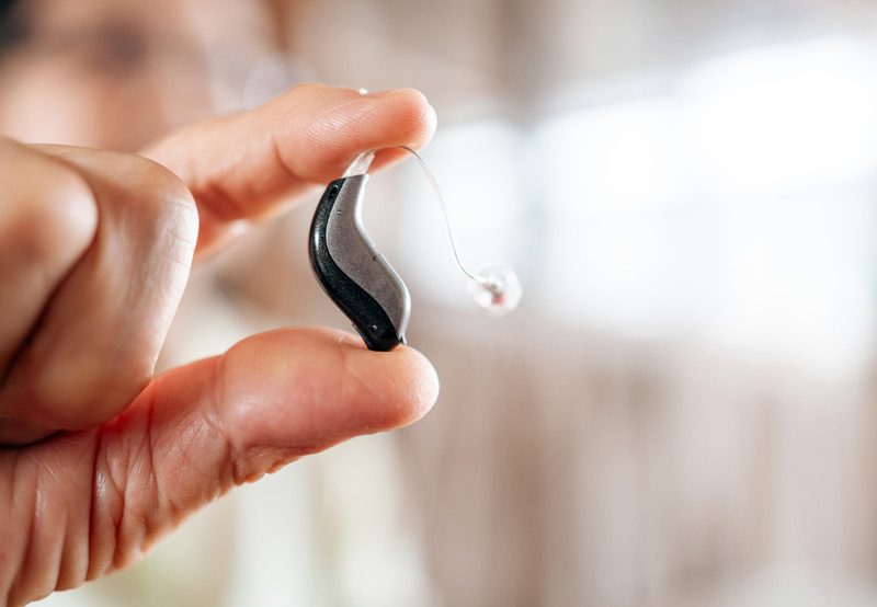 Hand-holding-small-hearing-aid-device Hand-holding-small-hearing-aid-device